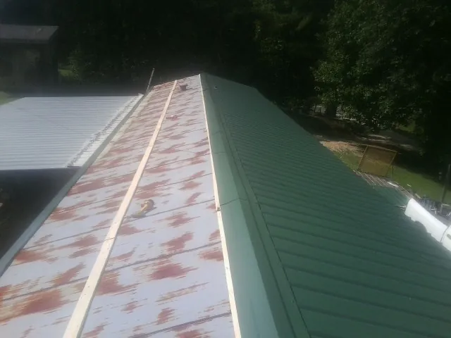 Old rusted panels beside newly installed green metal roofing — Wind Damage Roof Repair by Roofing Brothers in Hamden