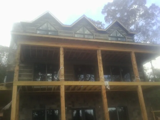 Dormers and porch framing on a large log home under construction — Roof Coating work by our crew in Hamden